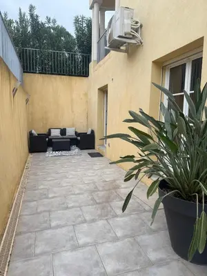 a patio with a couch and a potted plant at Bas de Villa à 15 min de Nice avec piscine in Carros