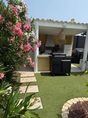 a backyard with a kitchen and a garden with pink flowers at Bas de Villa à 15 min de Nice avec piscine in Carros