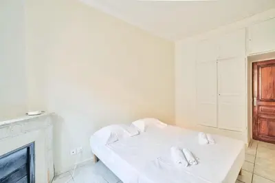 a white bedroom with a bed and a fireplace at Nidusudest - Spacieux appartement in Nice