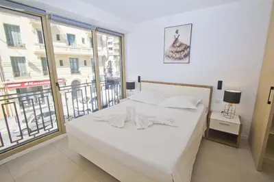 a bedroom with a white bed and a large window at Sea Front Palace Promenade in Nice