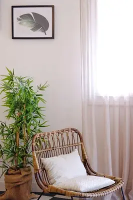 a rattan chair with a pillow and a plant at Beautiful flat with balcony and sea view in Saint-Laurent-du-Var