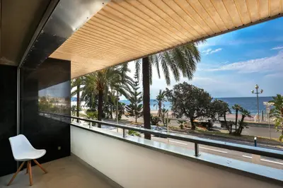 a room with a large window with a white chair and the ocean at Incroyable vue mer, 2 pièces refait à neuf avec piscine sur le toit/ WIFI/AC in Nice