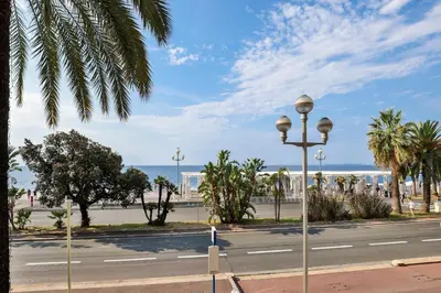 a street with palm trees and the ocean in the background at Incroyable vue mer, 2 pièces refait à neuf avec piscine sur le toit/ WIFI/AC in Nice