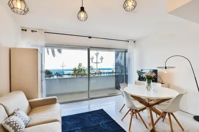 a living room with a table and chairs and a large window at Incroyable vue mer, 2 pièces refait à neuf avec piscine sur le toit/ WIFI/AC in Nice