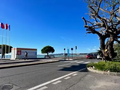 an empty road next to the ocean with a tree at Nice Seaside Pool and Tennis in Nice