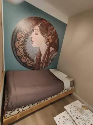 a room with a bed with a painting of a woman at «l’Orient Express» joli 2 pièces fonctionnel in Nice