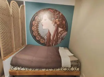 a bedroom with a bed with a painting of a woman at «l’Orient Express» joli 2 pièces fonctionnel in Nice