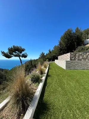 a garden with a retaining wall and a lawn at Èze - Appartement dans bas de villa avec piscine près de Monaco in Èze