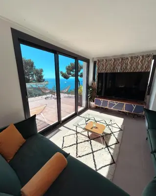 a living room with a couch and a view of the ocean at Èze - Appartement dans bas de villa avec piscine près de Monaco in Èze