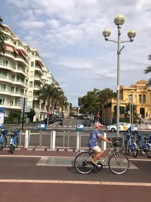 a person riding a bike on a city street at Promenade des anglais 20 mètres in Nice