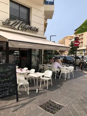 a restaurant with white tables and chairs on a sidewalk at Promenade des anglais 20 mètres in Nice