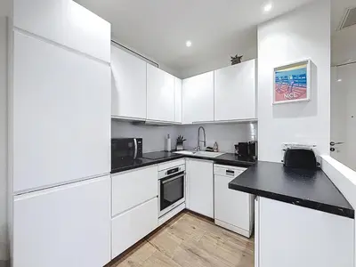 a kitchen with white cabinets and a black counter top at Le Francis - Riquier Port de Nice in Nice