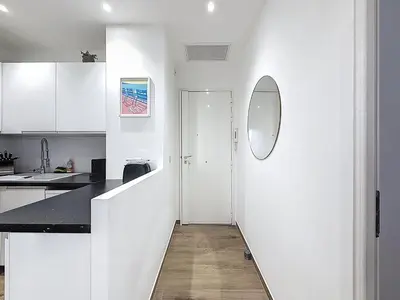 a white kitchen with white cabinets and a black counter top at Le Francis - Riquier Port de Nice in Nice