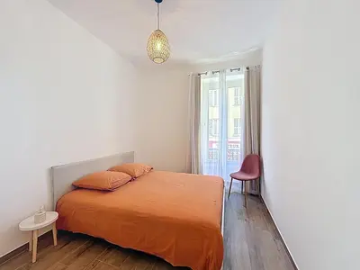 a bedroom with a bed and a red chair at Le Francis - Riquier Port de Nice in Nice