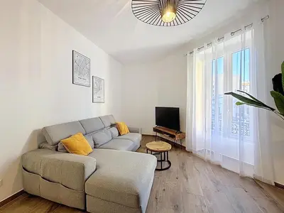 a living room with a couch and a television at Le Francis - Riquier Port de Nice in Nice