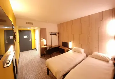 a hotel room with two beds and a desk at B&B HOTEL Nice Stade Riviera in Nice