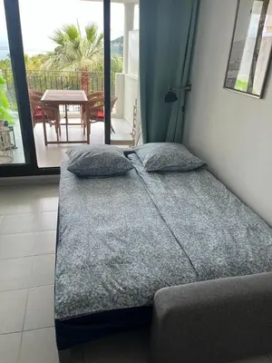 a bed with pillows in a room with a balcony at Pool , 150m to beach, seaview in Villefranche-sur-Mer