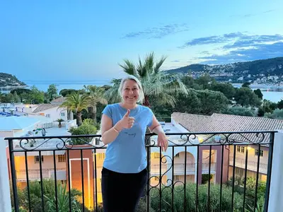 a woman standing on a balcony giving a thumbs up at Pool , 150m to beach, seaview in Villefranche-sur-Mer