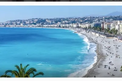 a view of a beach with people and the ocean at Charmant deux pièces dans le quartier du Port in Nice