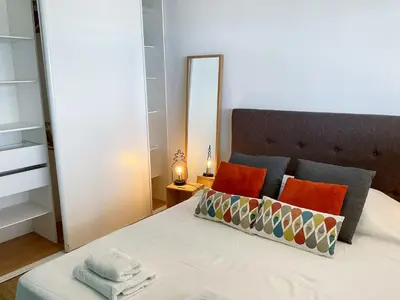 a bedroom with a bed with orange pillows and a mirror at La Prom 2 - a two bedroom apartment with a sea view in Nice