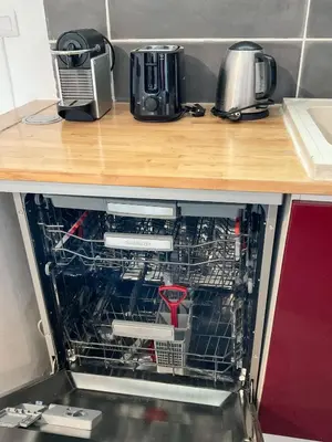 an open dishwasher in a kitchen with some appliances at La Prom 2 - a two bedroom apartment with a sea view in Nice