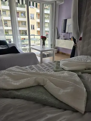 a bedroom with two beds and a table and a window at Gloria apartments in Nice