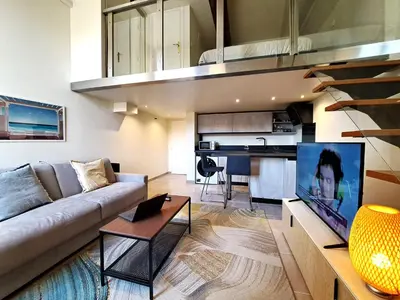 a living room with a couch and a tv and a kitchen at Massena square View 2 min to the beach & the old town in Nice