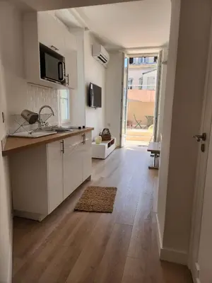 a kitchen with white cabinets and a wooden floor at AMAZING STUDIO - GRANDE TERRASSE - COEUR DE VILLE - WIFI - AC in Nice