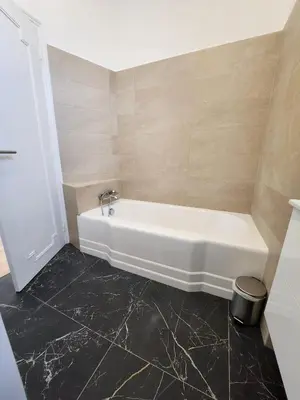 a white bath tub in a bathroom with black tiles at AMAZING STUDIO - GRANDE TERRASSE - COEUR DE VILLE - WIFI - AC in Nice