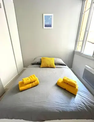a bed with two yellow pillows in a room at Congrès Résidence in Nice