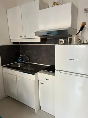 a white kitchen with a sink and a refrigerator at Studio lumineux avec balcon à proximité de la mer in Nice