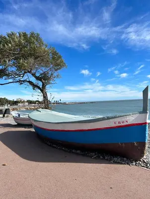 a boat sitting on the beach next to the ocean at Riviera 1 ou Riviera 2 ou réservez les 2 Front de Mer Cagnes sur Mer Promenade de la plage in Cagnes-sur-Mer