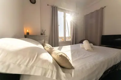 a bedroom with a white bed with pillows and a window at NICE CENTRE-VILLE STUDIO en étage in Nice