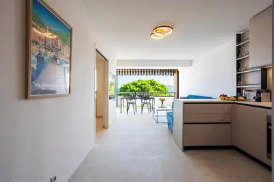 a kitchen and dining room with a view of a table at Agrianthe Palmiers AP4380 By Riviera Holiday Homes in Villefranche-sur-Mer