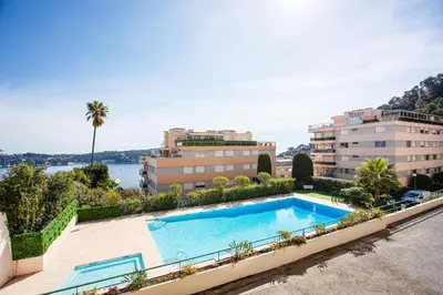 an image of a swimming pool in front of buildings at Agrianthe Palmiers AP4380 By Riviera Holiday Homes in Villefranche-sur-Mer