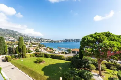 a park with a view of the water at Agrianthe Palmiers AP4380 By Riviera Holiday Homes in Villefranche-sur-Mer