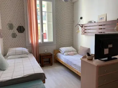 a bedroom with two beds and a tv and a window at appartement cosy in Nice