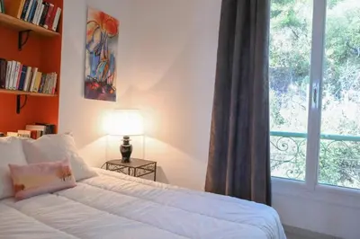 a bedroom with a bed with a window and a lamp at Les Lucioles - Vue mer, AC, Wi-Fi, 4 pers in Villefranche-sur-Mer