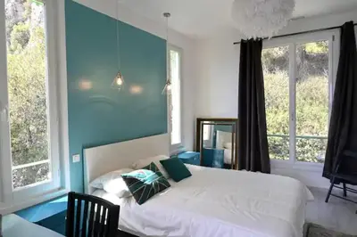 a bedroom with a white bed with a blue wall at Les Lucioles - Vue mer, AC, Wi-Fi, 4 pers in Villefranche-sur-Mer