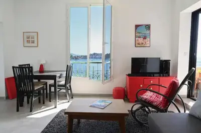 a living room with a table and chairs and a television at Les Lucioles - Vue mer, AC, Wi-Fi, 4 pers in Villefranche-sur-Mer