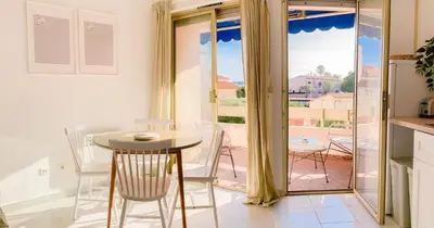 a kitchen with a table and chairs and a balcony at Cozy Beachside Apartment in Cros de Cagnes - Luna in Cagnes-sur-Mer