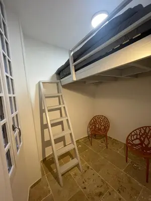a room with a ladder and a bed and two chairs at Vieux-Nice 3 pièces confortable et calme in Nice