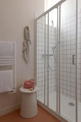 a bathroom with a glass shower and a stool at SLO Hostel Nice in Nice