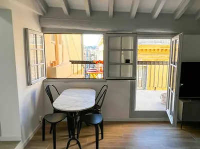 a small table and chairs in a room with a window at Beautiful Top Floor & Terrasse (Beach 1' walk) in Nice