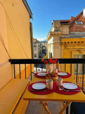 a table with plates and coffee cups on a balcony at Beautiful Top Floor & Terrasse (Beach 1' walk) in Nice