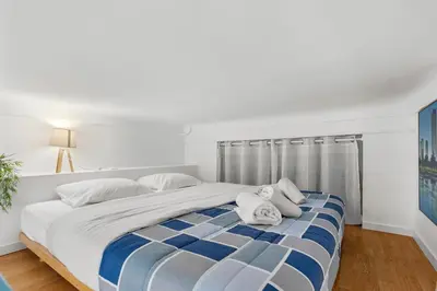 a white bedroom with a large bed with blue stripes at Studio Azur FSH in Nice