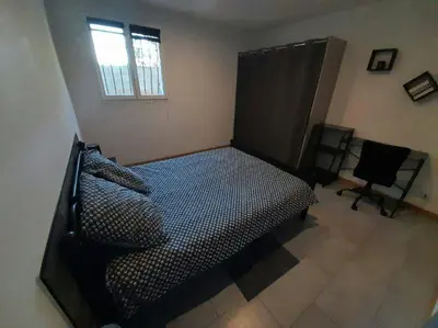 a bedroom with a bed and a chair and a window at Appartement spacieux &très calme. Spacious & very quiet apartment. in Carros