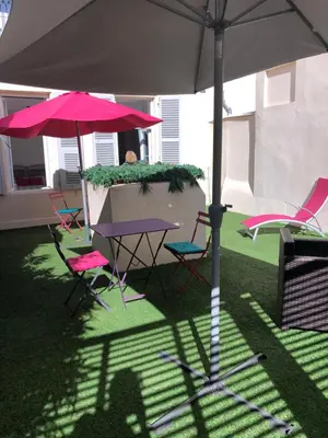 a person sitting at a table under an umbrella at Superbe 2 pièces Carré d’or avec grande Terrasse in Nice