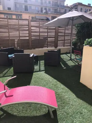 a pink chair and an umbrella on a balcony at Superbe 2 pièces Carré d’or avec grande Terrasse in Nice