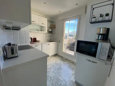 a white kitchen with a refrigerator and a window at Magnifique vue mer la Californie in Nice